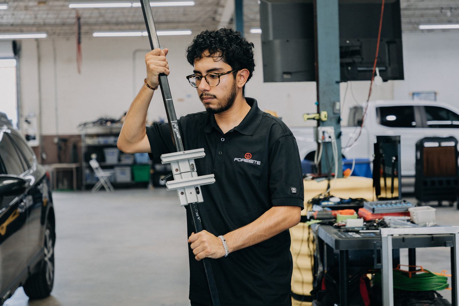 Technician carrying ADAS calibration equipment across the shop floor